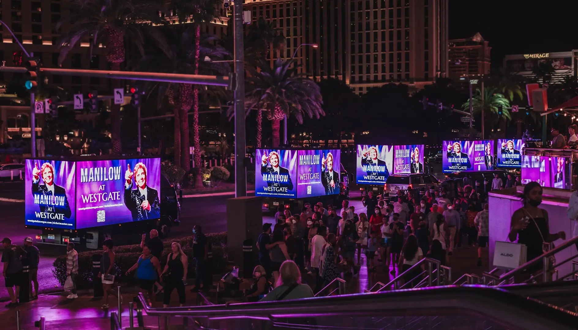 Multiple LED mobile billboard trucks lined up on a busy Las Vegas boulevard reaching thousands of pedestrians