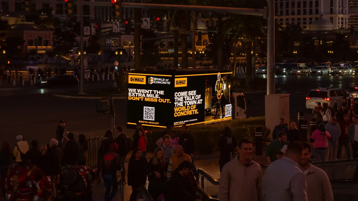 Mobile billboard truck advertising a construction trade show on a busy Las Vegas intersection with crowds
